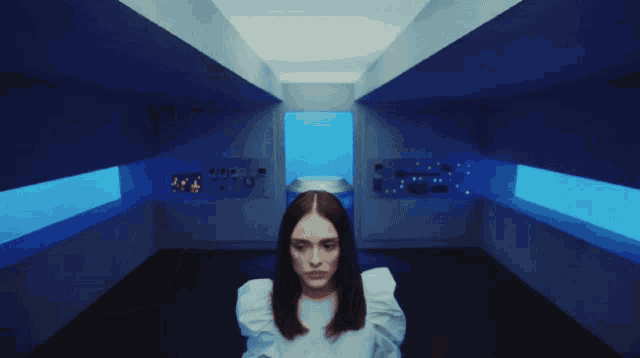a woman in a white shirt stands in front of a blue background