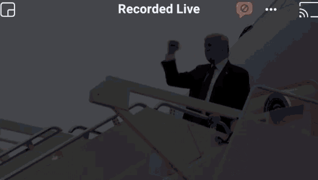 a man in a suit and tie is standing on the stairs of a plane .
