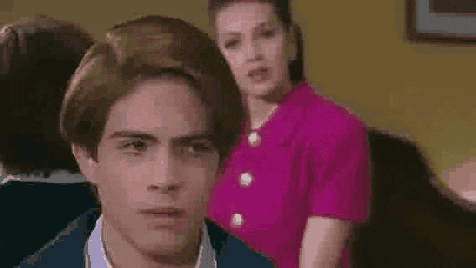 a woman in a pink shirt and earrings is talking to someone .