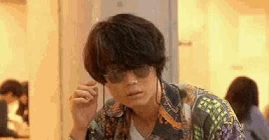 a young man wearing sunglasses and headphones is sitting in a room .