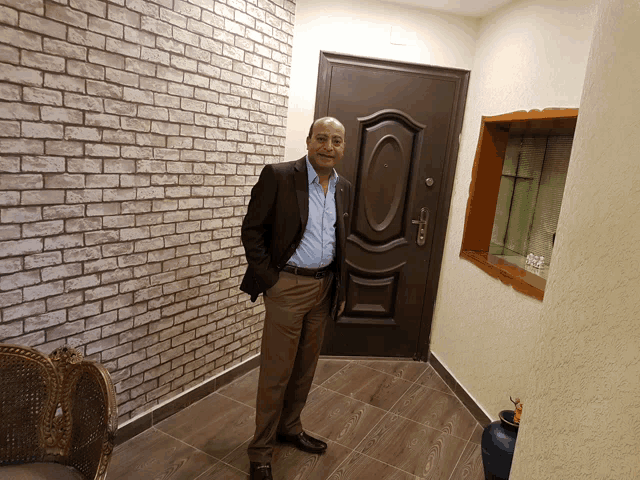 a man in a suit stands in front of a door in a hallway