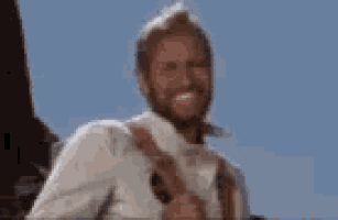 a man with a beard is smiling while holding a gun in his hand .