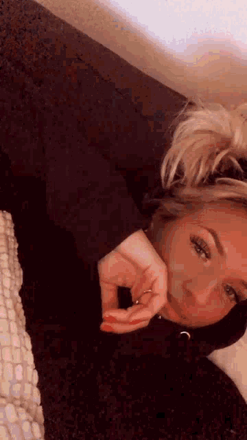 a woman laying on a couch with her hand on her chin