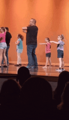 a group of young girls are dancing on a stage with a man