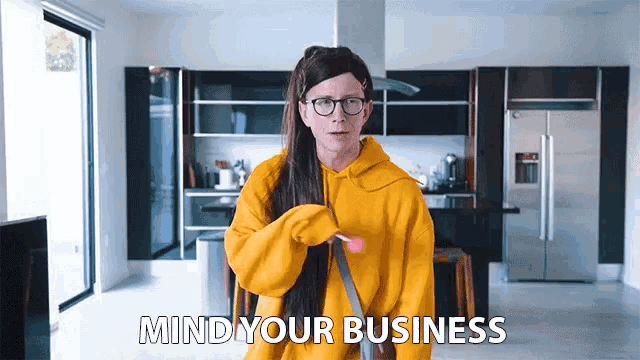 a woman in a yellow hoodie says mind your business in a kitchen