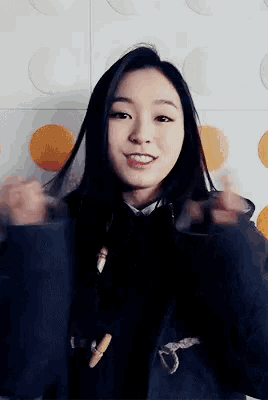 a young woman in a black jacket is smiling and making a funny face