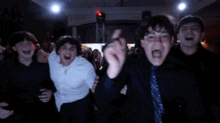 a group of boys are dancing in a dark room with red lights