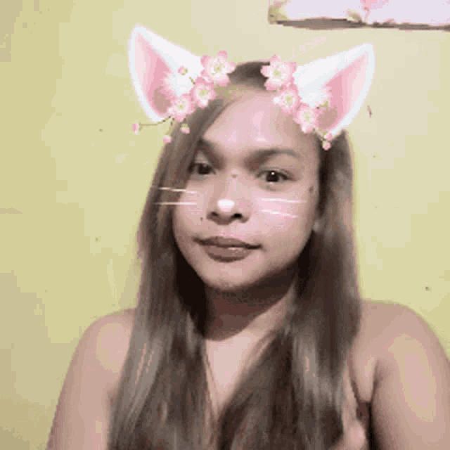 a woman with cat ears and flowers on her face looks at the camera