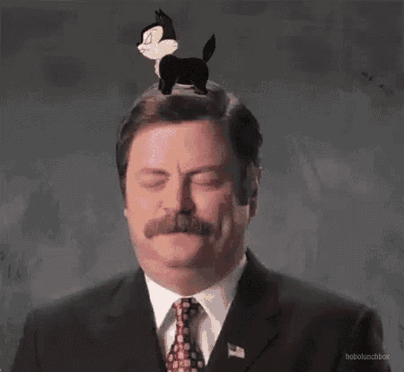 a man in a suit and tie has a cartoon character on his head .