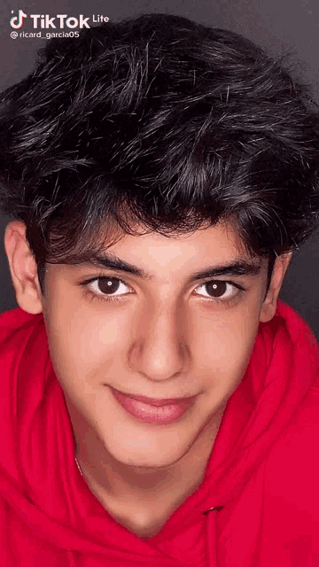 a young man in a red hoodie is smiling for the camera