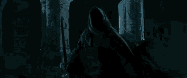 a man with long hair and a beard is holding a torch in a dark room .