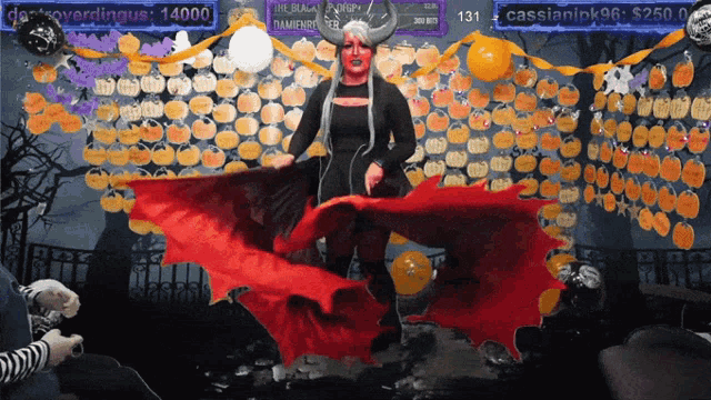 a woman in a vampire costume stands in front of a wall of pumpkins and a sign that says cassianick96