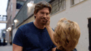 a woman touches a man 's face in a blue shirt