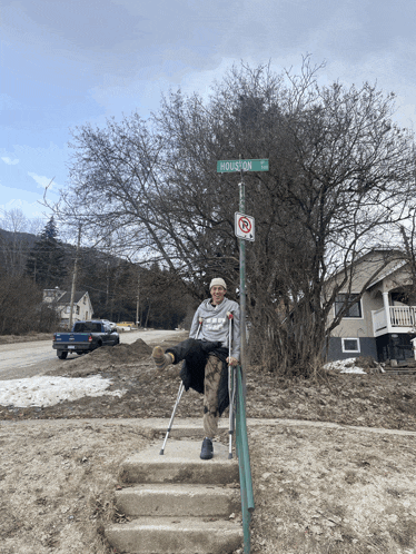 a man with crutches sits on a set of stairs under a sign that says houston