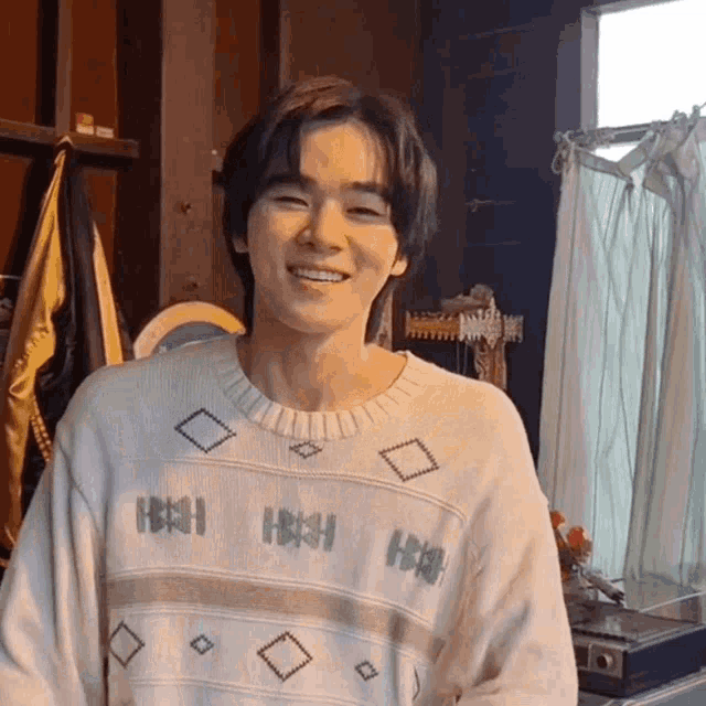 a young man wearing a sweater that says hhh is smiling