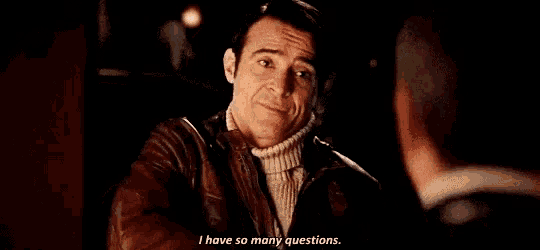 a man in a leather jacket is talking to another man in a dark room and saying `` i have so many questions . ''