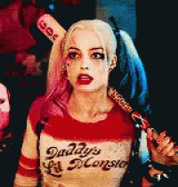 harley quinn from suicide squad is wearing a daddy 's monster shirt and holding a bat .