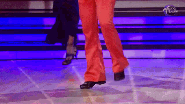 a woman in red pants is dancing in front of a dancing brasil sign