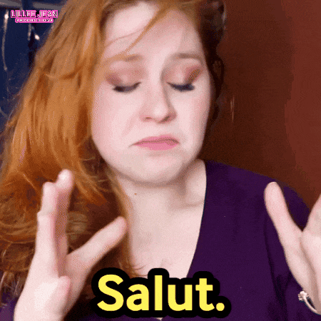 a woman with red hair is making a peace sign and the word salut is above her