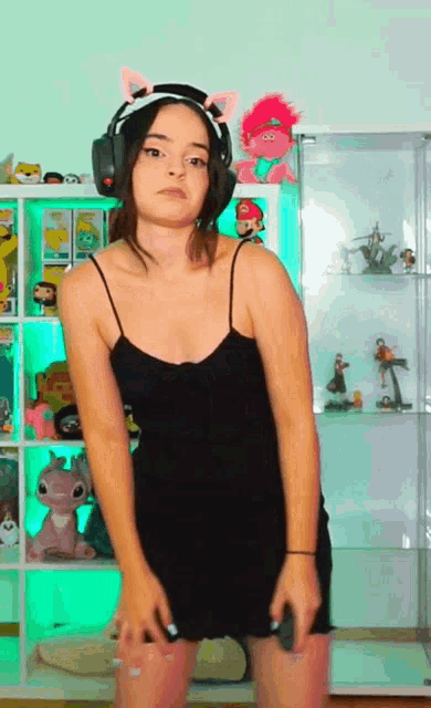 a woman in a black dress and headphones is dancing