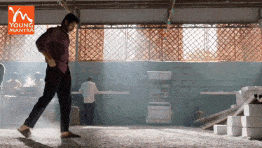 a man is dancing in a room with a young mantra logo in the background