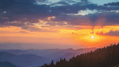 the sun is setting over a mountain range