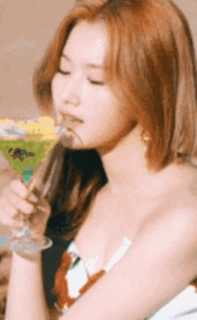 a woman is holding a martini glass in her hand and drinking it .