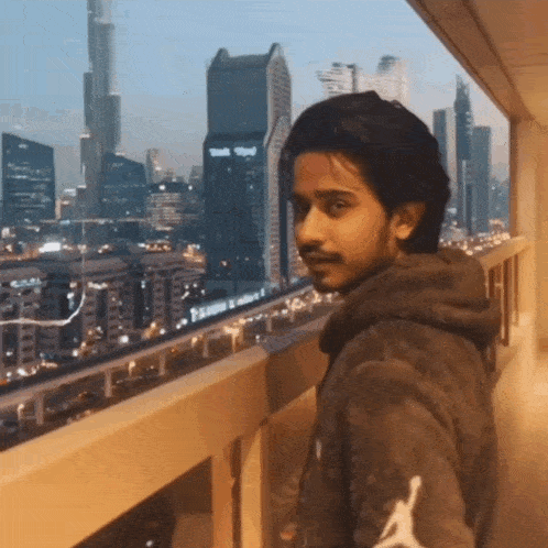 a man standing on a balcony looking out over a city skyline