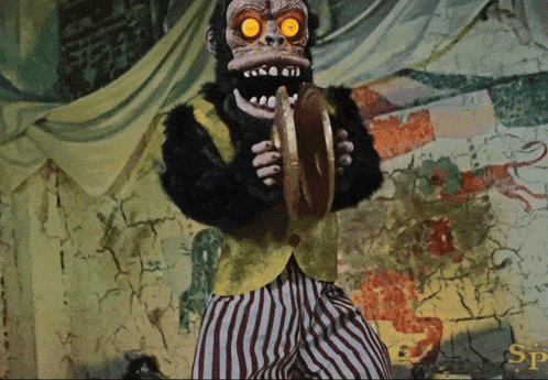 a monkey holding a cymbal in front of a wall with the letter sp on it