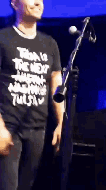 a man in a tulsa shirt stands in front of a microphone on a stage