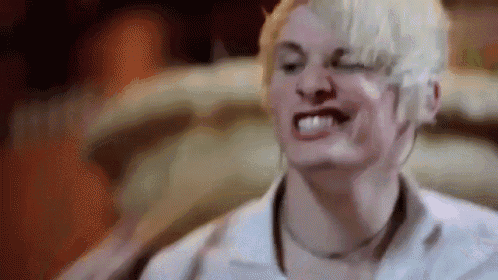a man with short blonde hair is making a funny face while wearing a white shirt .