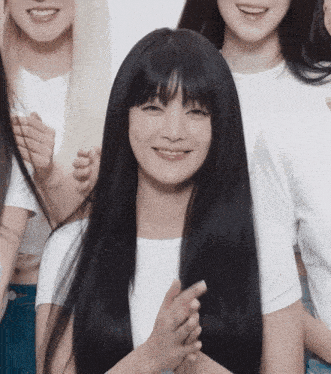 a woman with long black hair is smiling and clapping