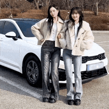 two women standing in front of a white kia