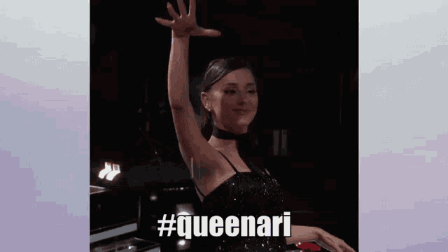 a woman in a black dress is waving her hand and the words queenari are on the bottom of the image .