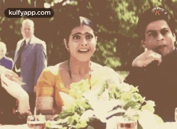 a man and a woman are standing next to each other in front of a table full of flowers .