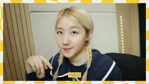a girl with blonde hair is sitting in front of a yellow and white checkered wall