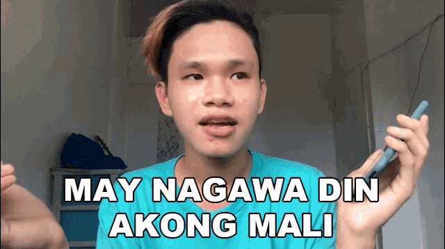 a man in a blue shirt is holding a cell phone and says may nagawa din akong mali in white letters