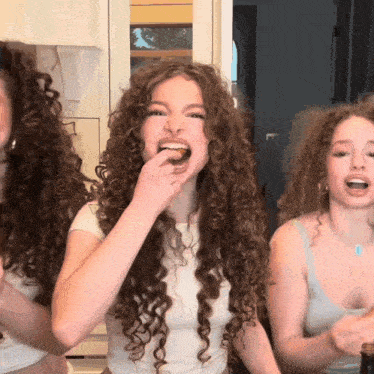 a girl with curly hair is eating a cookie