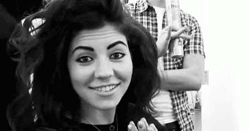 a woman is smiling in a black and white photo while a man is holding a spray can .