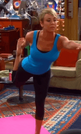 a woman in a blue tank top is doing yoga on a pink mat in a living room