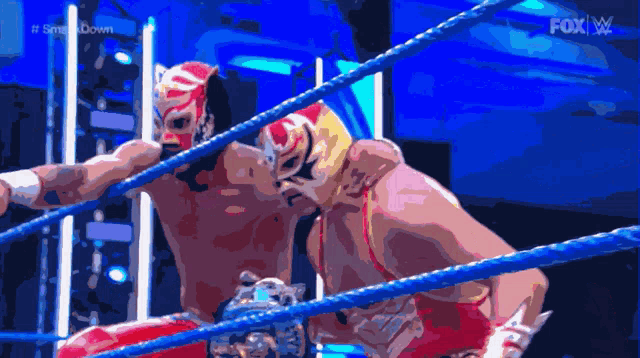 two masked wrestlers in a ring with the fox logo on the bottom right