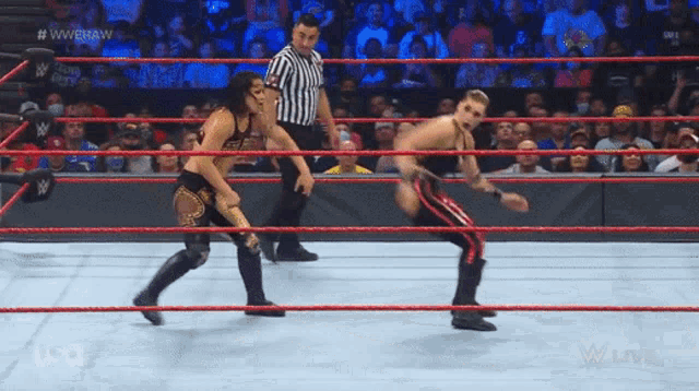 two wrestlers are in a wrestling ring with a referee standing behind them