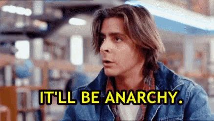 a man in a denim jacket is sitting in a library and says `` it 'll be anarchy '' .