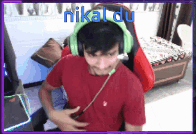 a man wearing headphones and a red shirt is sitting in a chair with the words nikal du written on the bottom