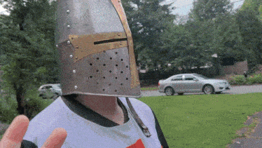 a person wearing a knight 's helmet stands in front of a car