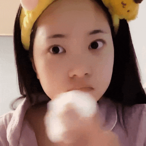 a girl wearing a headband with a cat on it looks at the camera