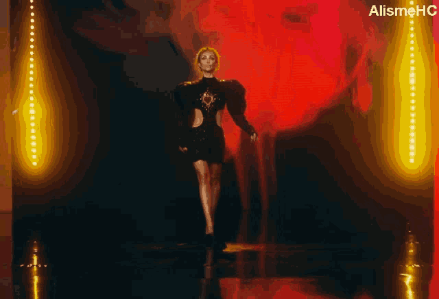 a woman in a black dress walks down a runway in front of a sign that says alismehc on it