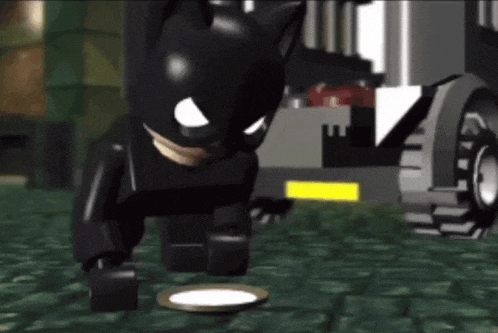 a lego batman is standing next to a plate