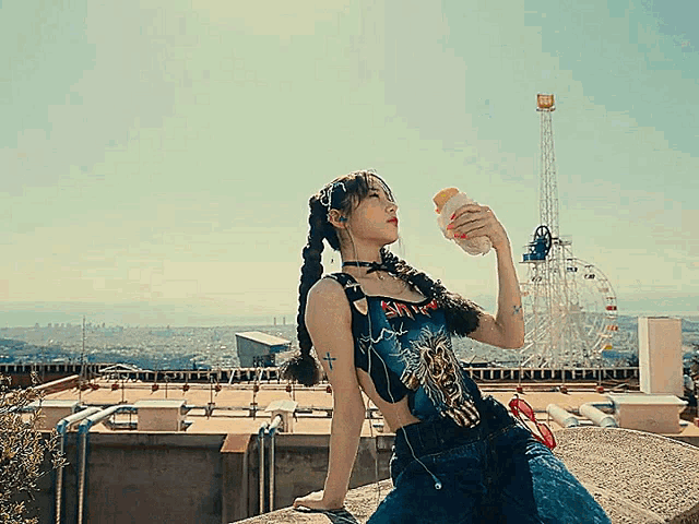 a woman sitting on a rooftop drinking from a bottle