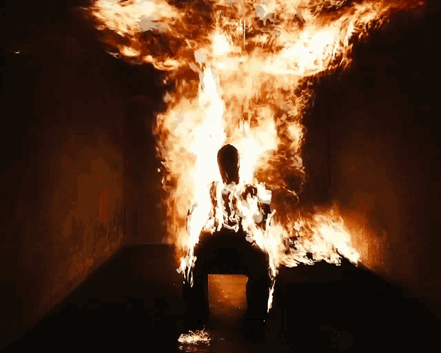 a person is burning in a dark room with a lot of flames